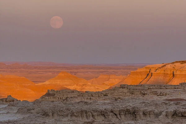 USA, South Dakota, Badlands National Park. Moonrise over rugged landscape at sunset