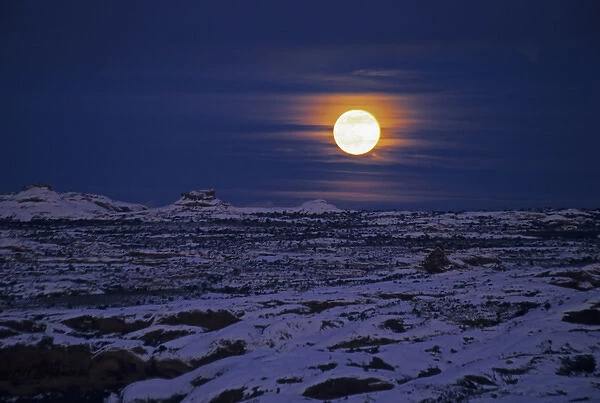 USA, Utah, Arches National Park. Full moon rising over snow-covered landscape. Credit as