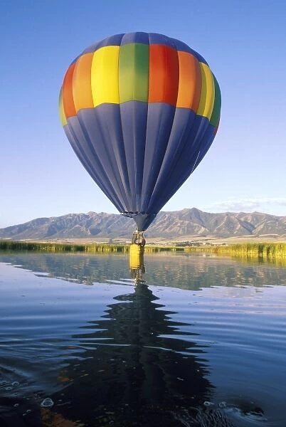 USA, Utah, Cache Valley. Basket of hot air balloon intentionally touches water of