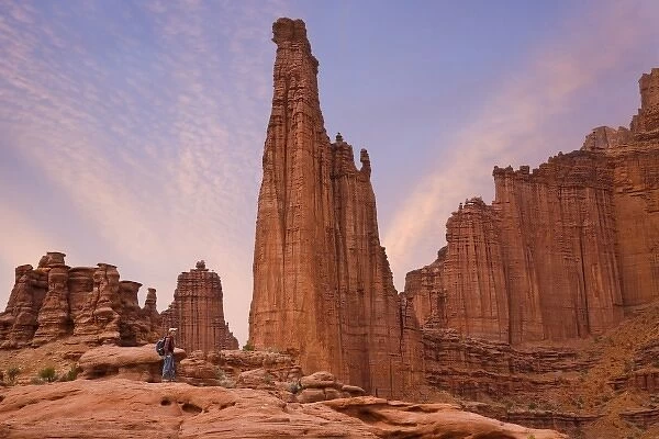 USA, Utah. Hiker watches sunset on Fisher Towers sandstone formations