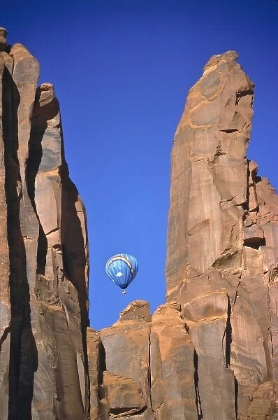 USA, Utah, Monument Valley. A rising hot air balloon is visible through the sculpted