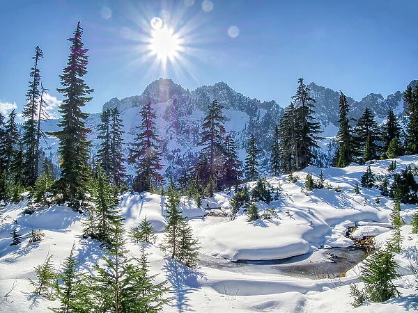 USA, Washington State, Alpine Lakes Wilderness. Frozen alpine pond with fresh snow and Cascade Range