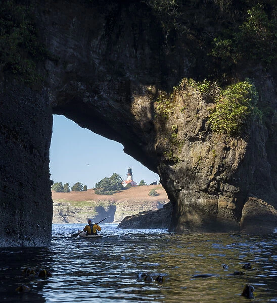 USA, Washington State. Male sea kayaker in archway at Cape Flattery, Olympic Coast