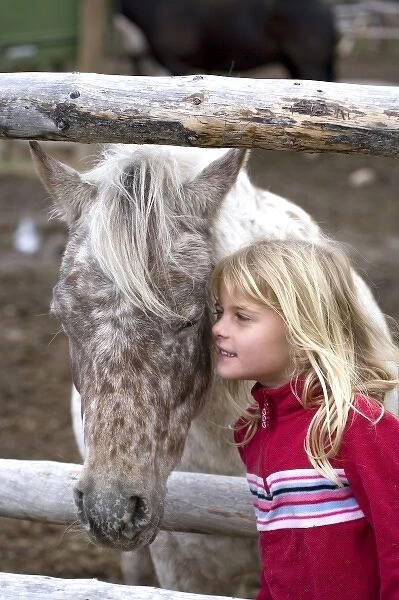 USA. Wyoming. Grand Tetons National Park. Young girl looks a spotted pony in the