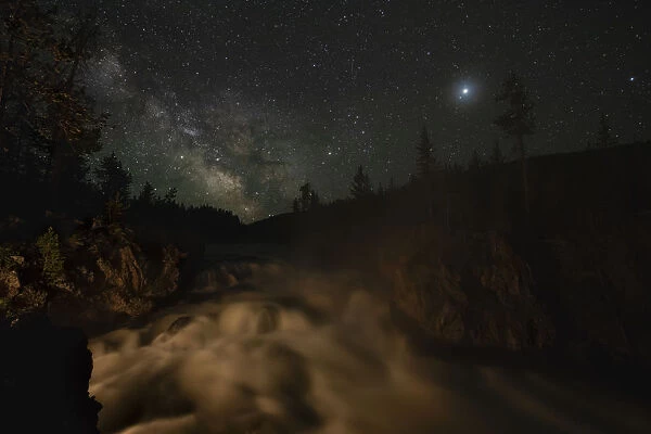 USA, Wyoming, Yellowstone National Park. Milky Way floats above a waterfall on the