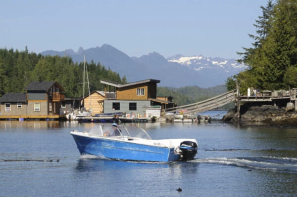Vancouver Island, Tofino. Motorboat passing in front of floating houses