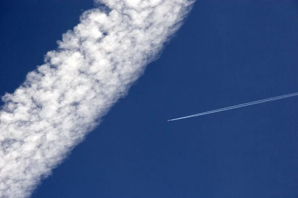 Vapor contrails from high flying jet aircraft. The larger has been blown apart by