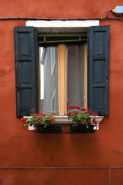 Venice, Veneto, Italy - Black wooden shutters and flowers in a planter frame a window