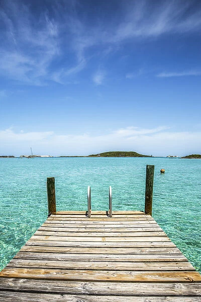 Vertical photo with a dock in the foreground, clear water and blue sky in the background