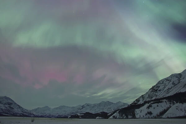 A vibrant display of Aurora Borealis fills the northern sky with a rainbow of colors