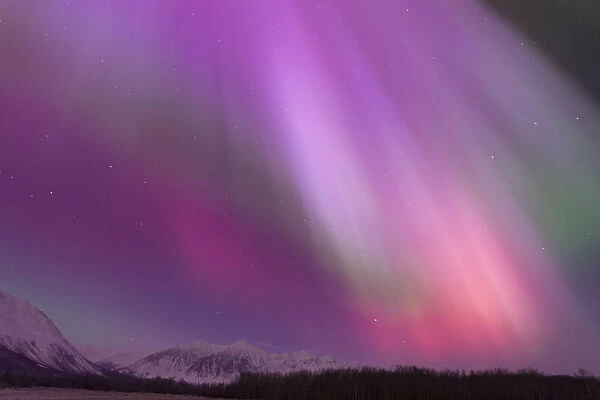 A vibrant display of Aurora Borealis fills the northern sky with a rainbow of colors