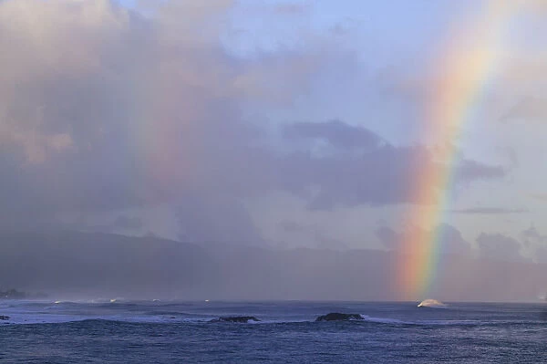Vibrant rainbow offshore, Pacific storm waves, North Shore of Oahu, Hawaii