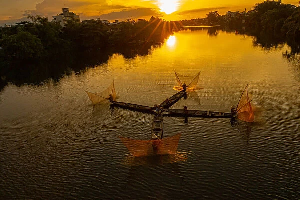 Vietnam. Coordinated lagoon fishing with nets at sunset