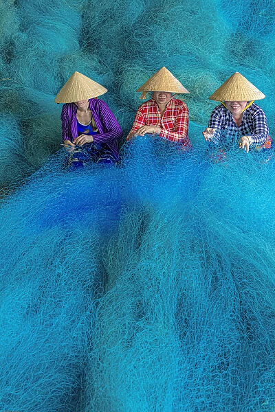 Vietnam. Women repairing fishing nets