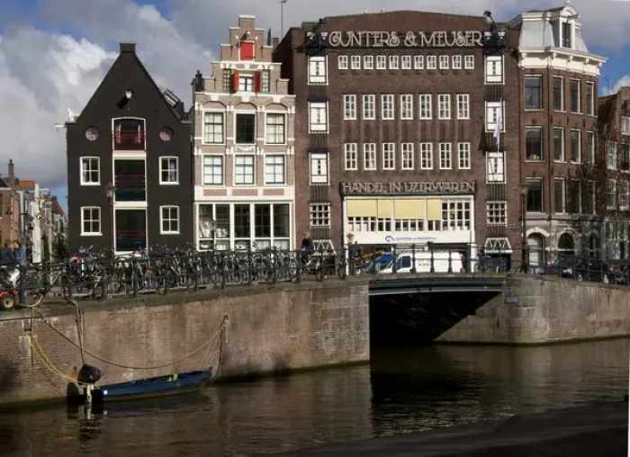 Framed Print : View from the Amstel of many parked bikes and the unique gable buildings