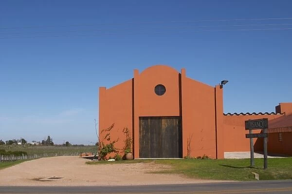 A view over the main winery building and a sign to the winery. Painted in ochre red