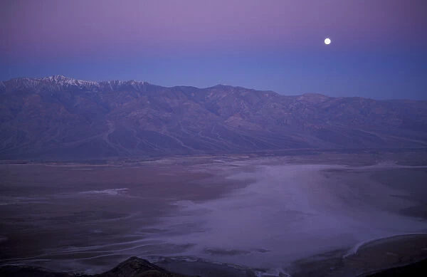 View of snow on Telescope Peak in Death Valley at sunrise with full moon descending