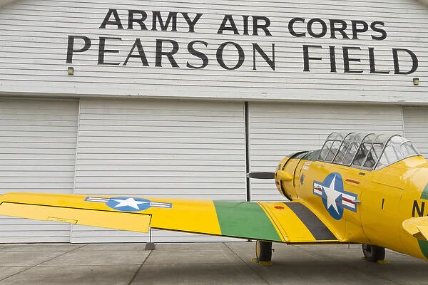 A vintage World War II military trainer aircraft parked at a hangar at Pearson Field