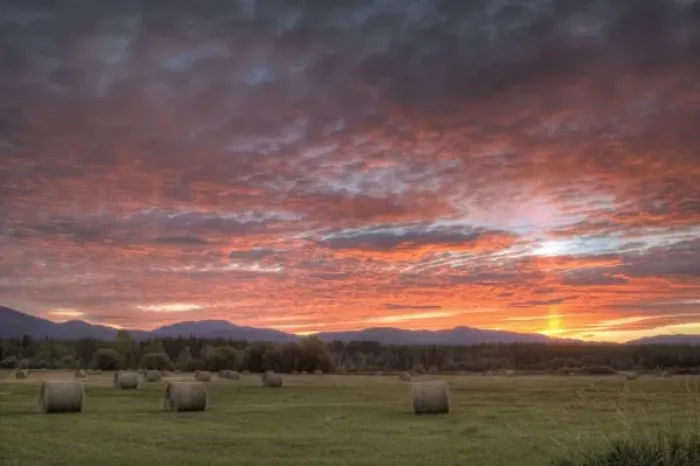 Framed Print : Vivid sunrise clouds over hay bales in field and the Whitefish Mountain Range in Montana