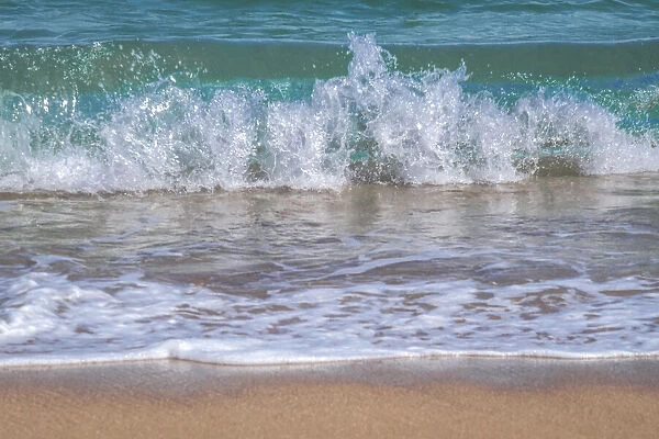 Wave crashing on golden sandy beach