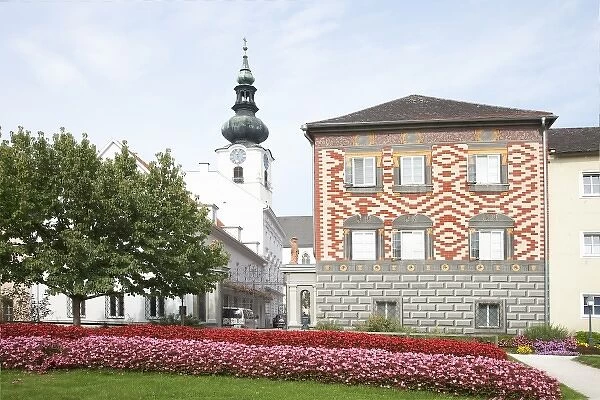 Wels, Upper Austria, Austria - Rows of red and pink flowers border a lawn in front of a building