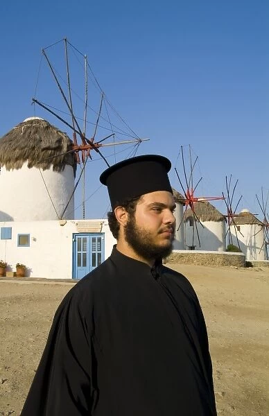 White and blue windmills with a Greek Orthodox priest on the island of Mykonos, Greece