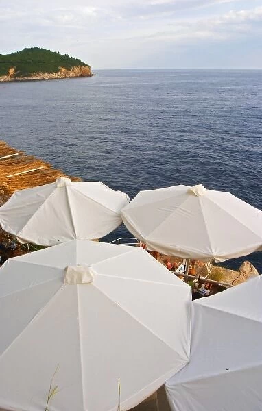 White sun shade umbrellas at a cafe on the city wall overlooking the sea and the