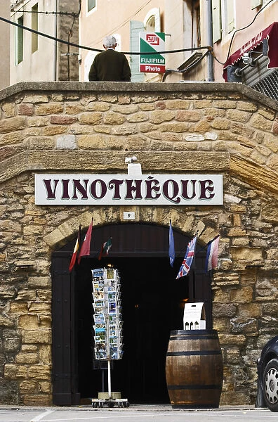 A wine shop vinotheque with flags, post cards on a stand and a barrel with wine bottles