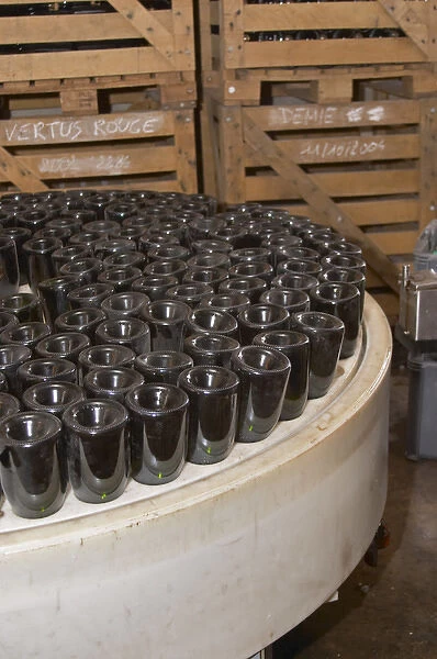 In the winery: bottles upside down in a machine that puts the neck in a salt solution