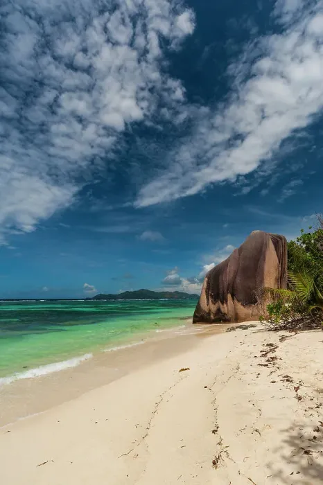 Framed Print : Wispy clouds over a sandy tropical beach with a large stone rock formation. Anse Source d Argent Beach, La Digue Island, Seychelles