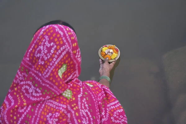 Woman putting flower lamp onto the Ganges River, Varanasi, India