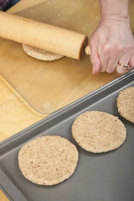 Framed Print : Woman rolling multigrain bread dough into circles to make hamburger buns. (MR) Framed Print : Woman rolling multigrain bread dough into circles to make hamburger buns. (MR)