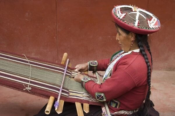Woman in traditional dress and hat weaving using a backstrap loom to weave, Chinchero