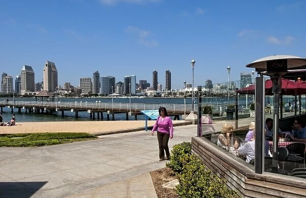 Woman walking on pavement with scenic of skyline of San Diego from Coronado Island
