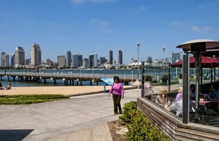 Framed Print : Woman walking on pavement with scenic of skyline of San Diego from Coronado Island