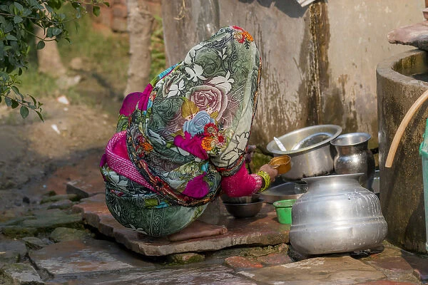 Woman washing dishes. Fatehpur Sikri village. Bharatpur. Rajasthan. India