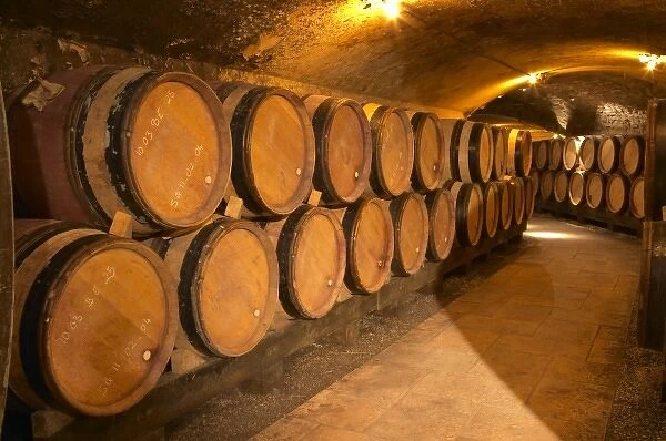 Wooden barrels with aging wine in an underground corridor in the cellar of Guigal in Ampuis
