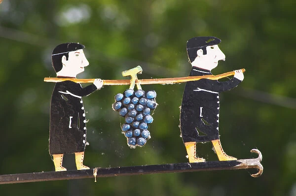 A wrought iron painted sign that illustrates the theme of champagne and wine production