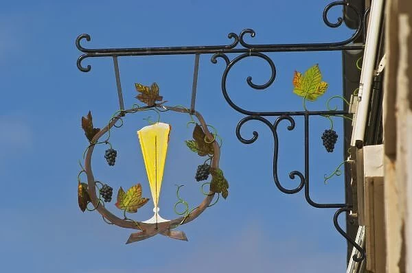 A wrought iron sign that illustrates the theme of champagne and wine production