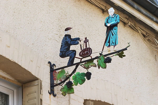A wrouight iron painted sign that illustrates the theme of champagne and wine production