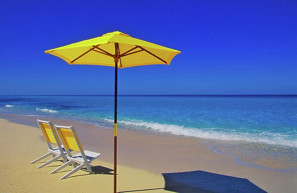 Yellow beach umbrella and chairs on pristine beach, Bimini Island, Bahamas