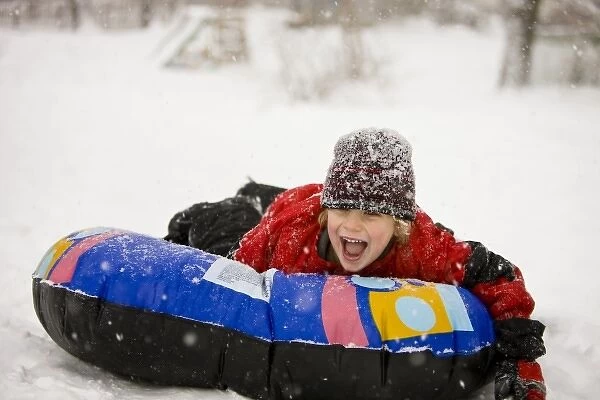 A young boy sledding on a snow tube during a snowstorm in Portsmouth, New Hampshire