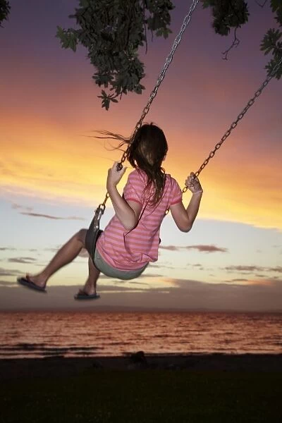 Young Girl on Rope Swing under Pohutukawa Tree at Sunset, Thames, Coromandel, North Island