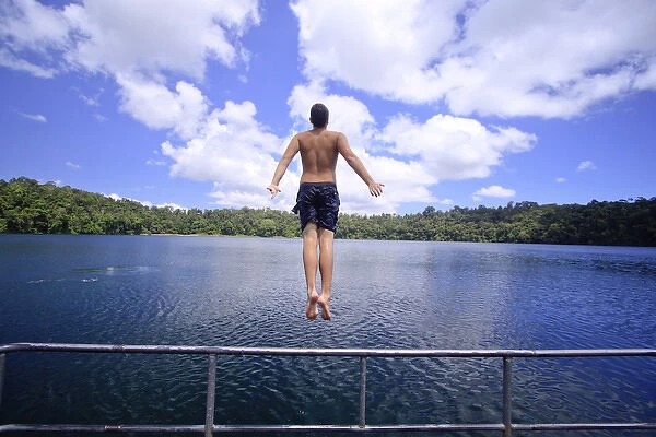 A young man jumps into the refreshing waters of Lake Eacham in the Crater Lakes National Park