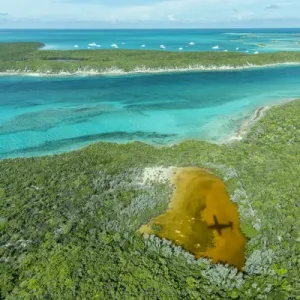 Aerial photo looking down at the airplanes shadow and clear tropical water