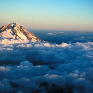 Aerial view of snow covered Mt. Hood poking through the clouds just at an Oregon sunset
