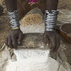 Africa, Ethiopia, Southern Omo, Karo Tribe. Woman grinding grain into flour with stone