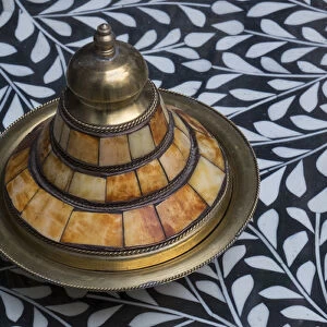 Africa, Morocco, Fes. A covered brass bowl with inlay of camel bone sites on a stone
