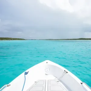 A boat drives through clear aquamarine waters near Staniel Cay, Exuma, Bahamas