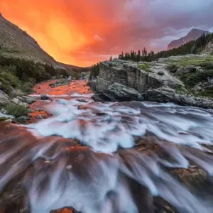 Brlliant sunrise sky over Swiftcurrent Falls in Glacier National Park, Montana, USA